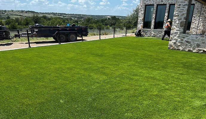 Residential artificial turf installation Workers installing an artificial turf lawn in a backyard.