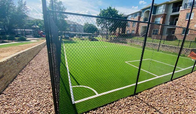 Community multi-use sports court Fenced-in artificial turf sports court at an apartment complex.