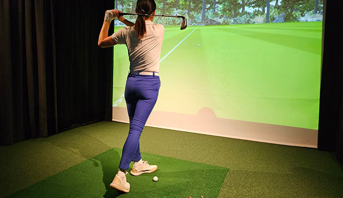 Woman playing golf in a golf simulator Woman playing golf in a golf simulator