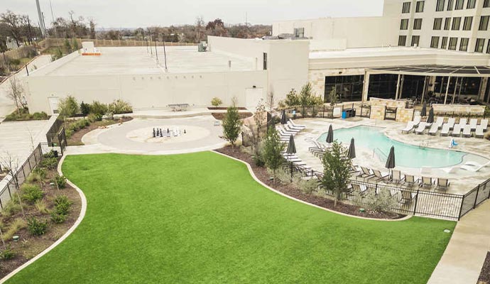 Hotel and resort amenity deck Hotel courtyard with a pool and an artificial turf lawn.