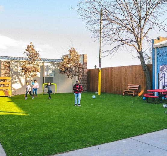 Urban multi-use play area People playing soccer in an urban courtyard with artificial turf.