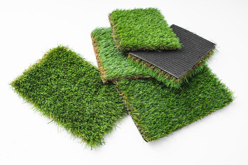 Stack of various artificial grass samples with different textures.